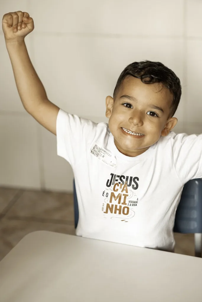 Menino com o braço erguido comemorando durante a aula bíblica do Haja Kids